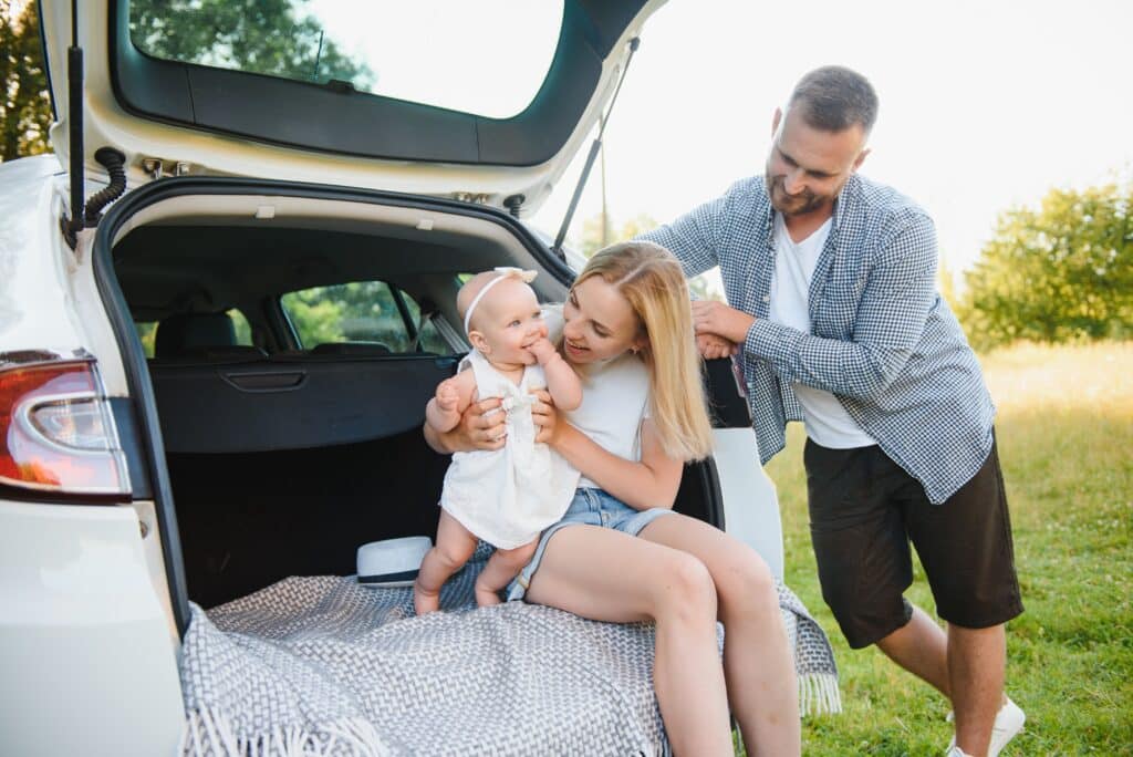 Family with kid sitting in car trunk