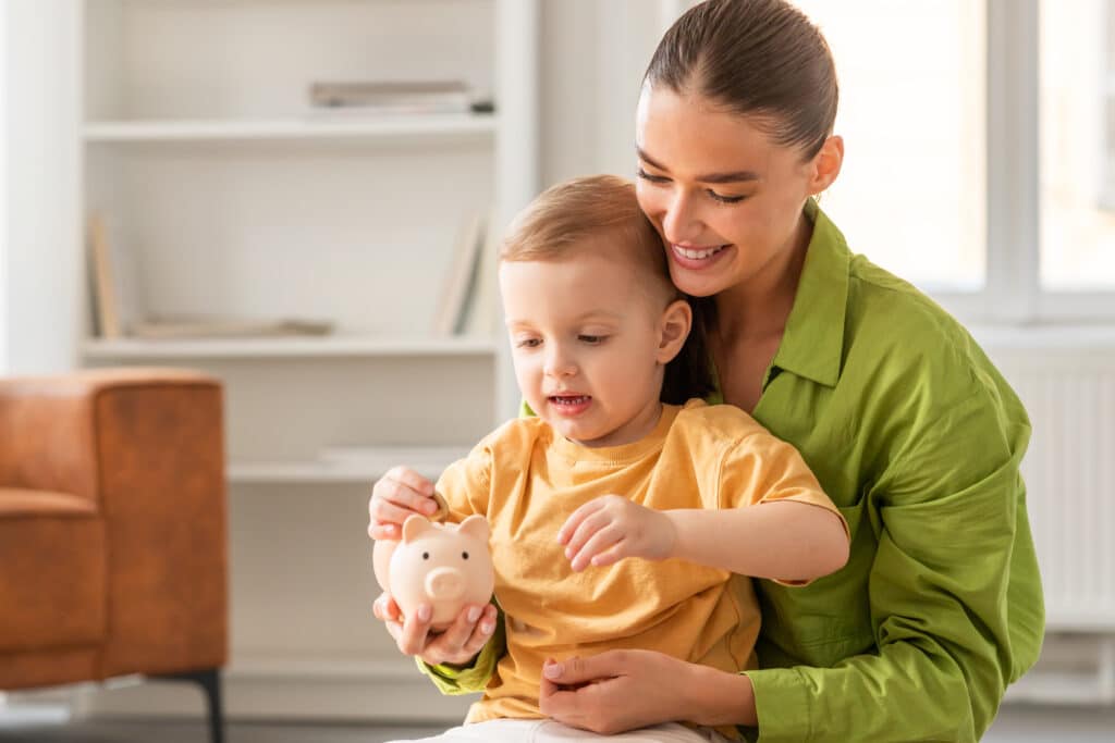 Woman Holding Child Holding Piggy Bank at Home